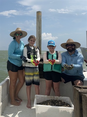 Blake Branson posing with a woman and two children holding oysters.