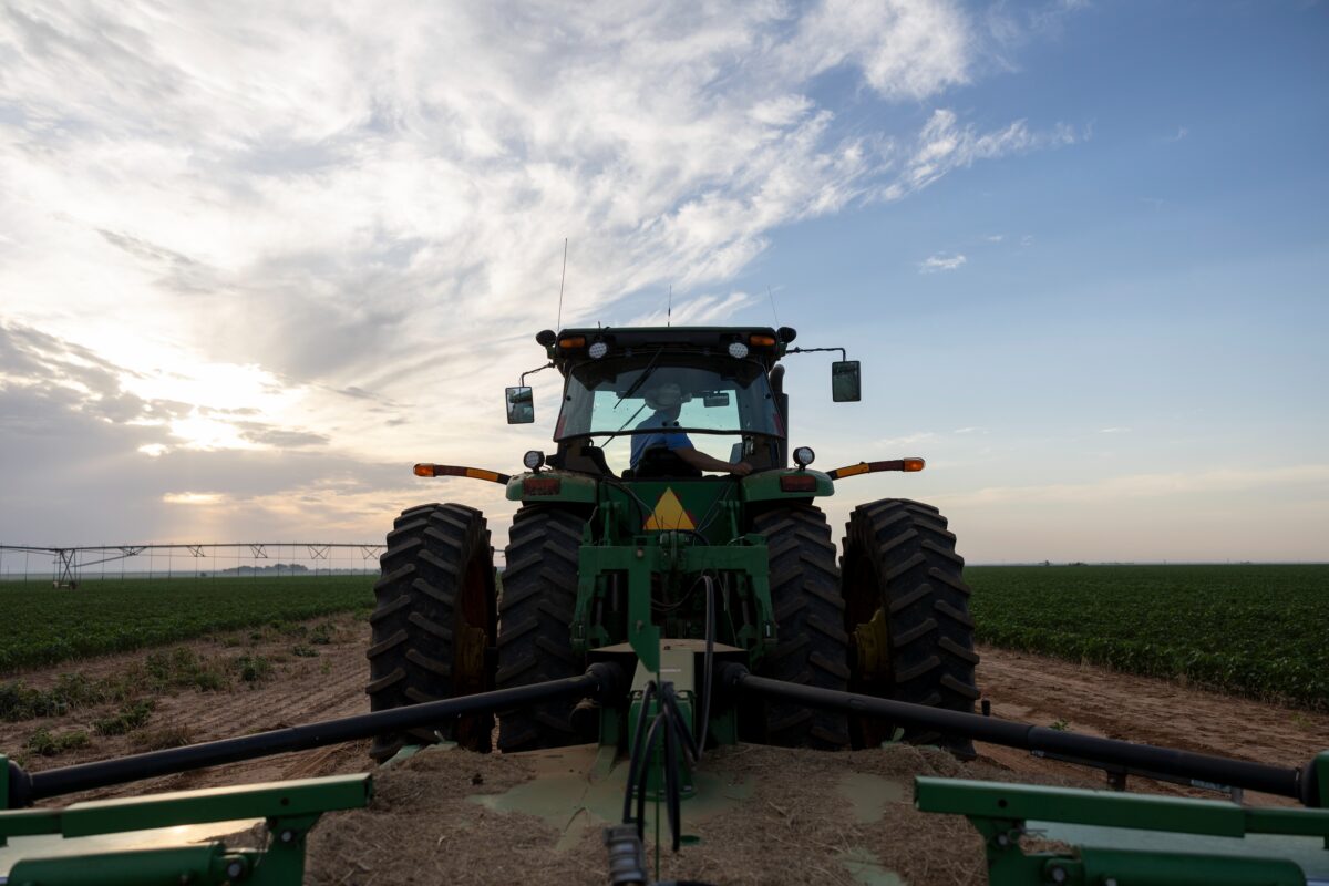 A tractor parked in the center of a green field under a clear blue sky.