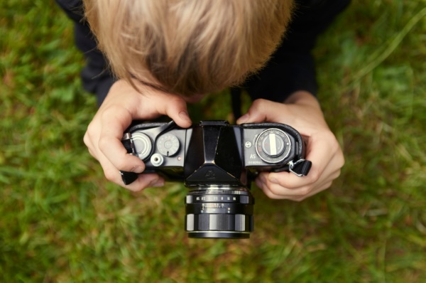 A person holding a camera, focused on taking a picture outdoors.