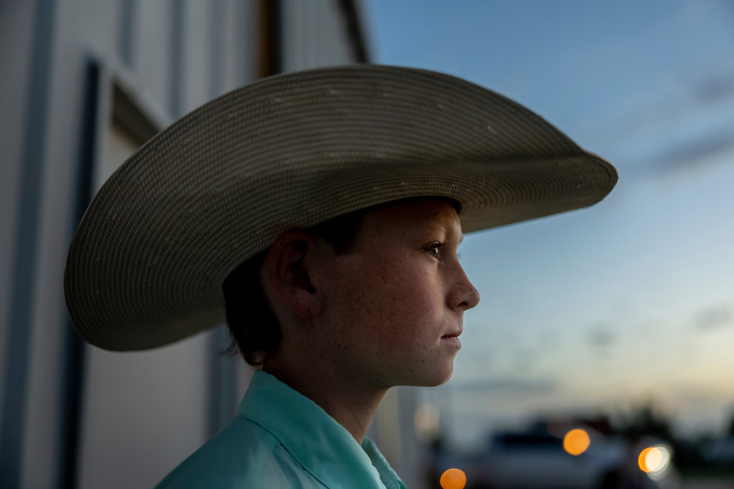 Young farmer in a straw hat looking into the distance at dusk.
