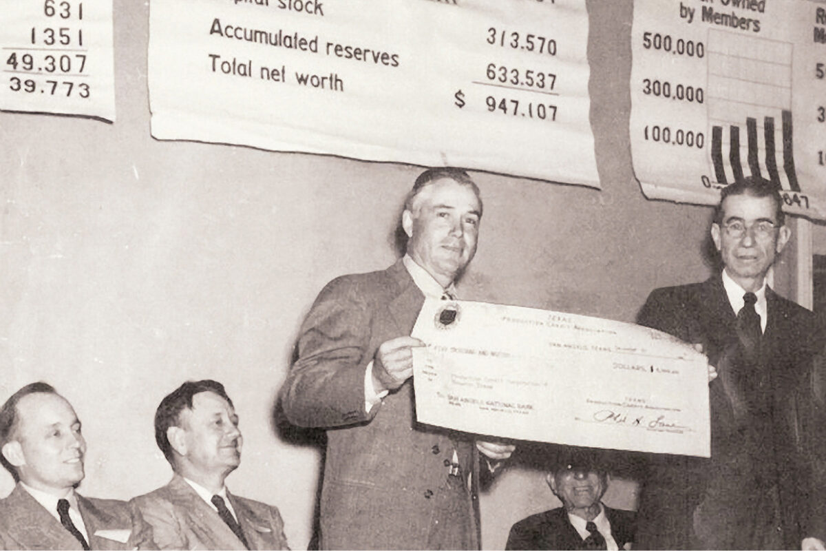 1940s, a man holds up a large check