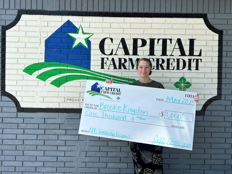 A CFC Youth Scholarship recipient holding up a $1,000 check