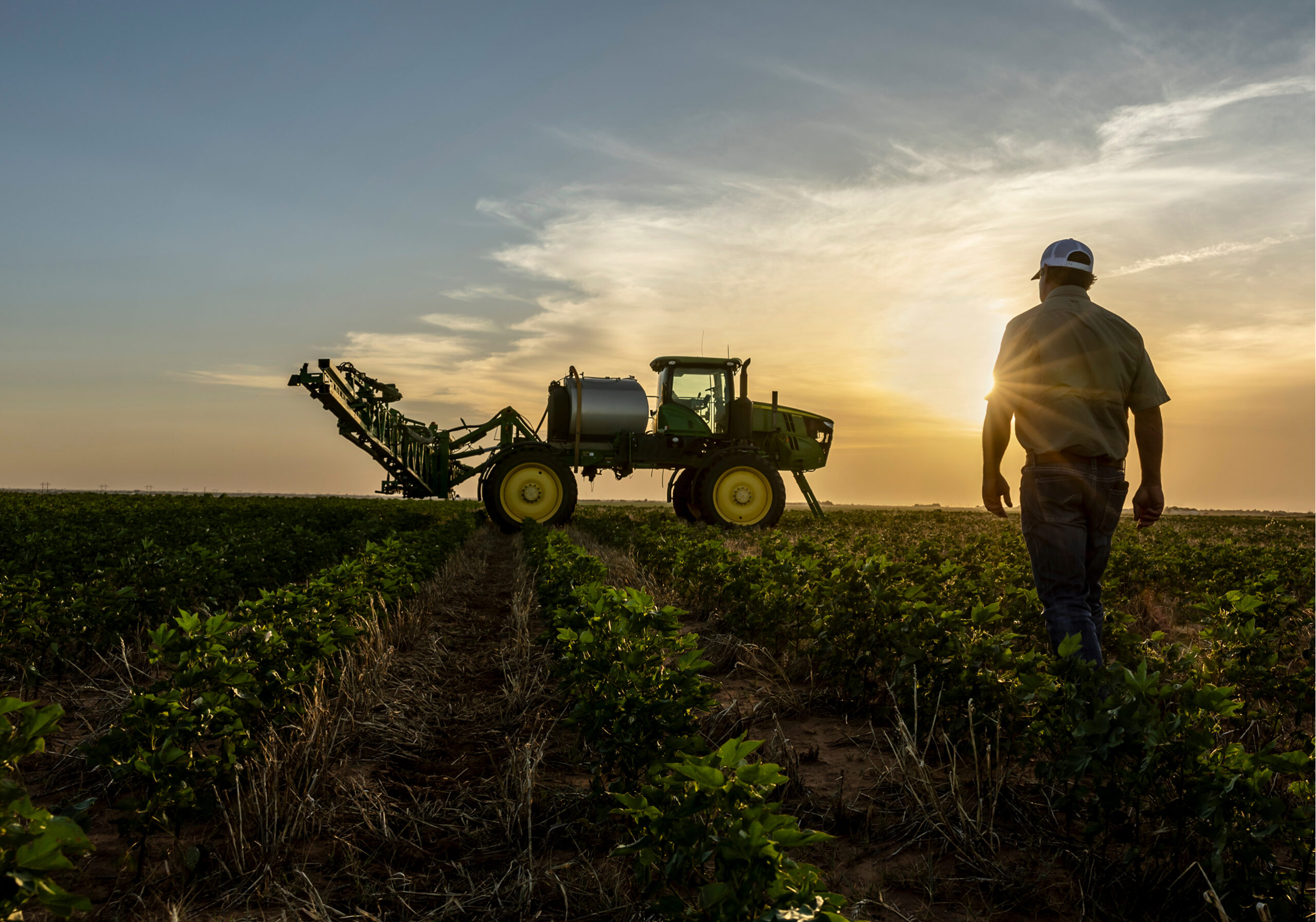 Farmer walking toward farming equipment at sunset