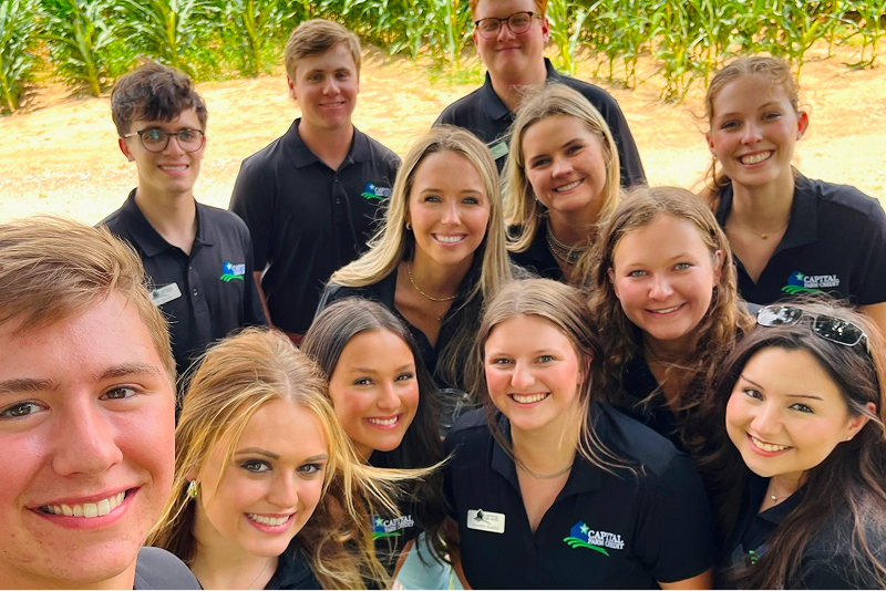 A group of Capital Farm Credit interns take a group selfie in front of a crop field