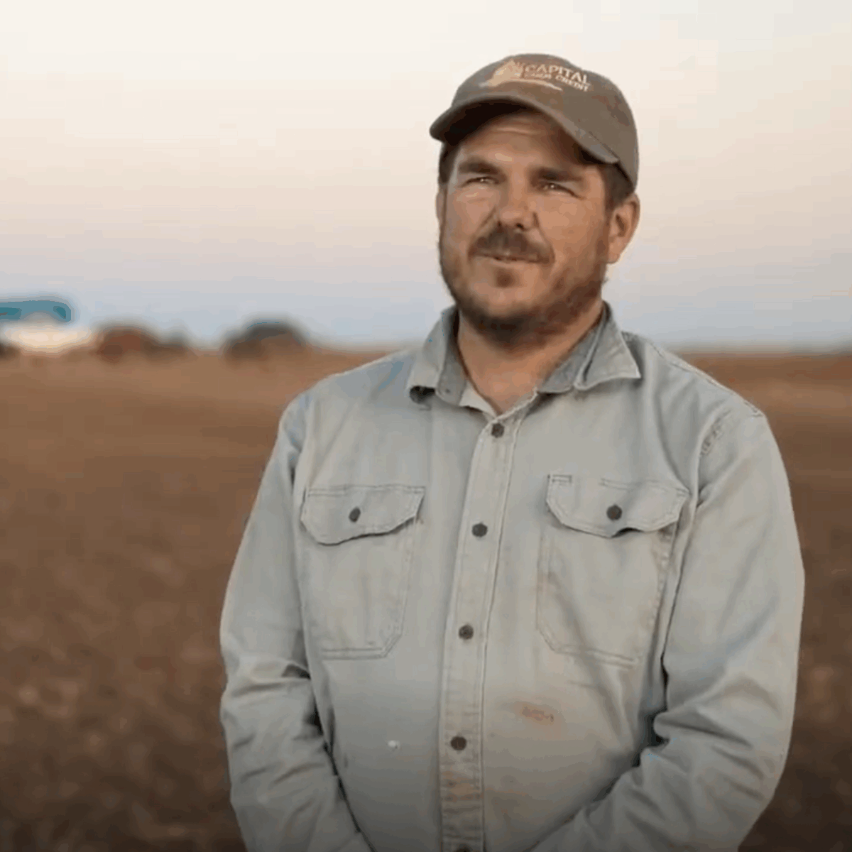 a farmer standing in front of a crop field