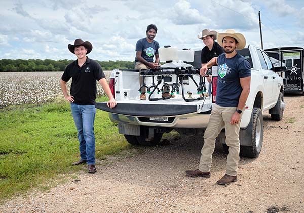Four ranchers gathered around a precision crop-spraying drone